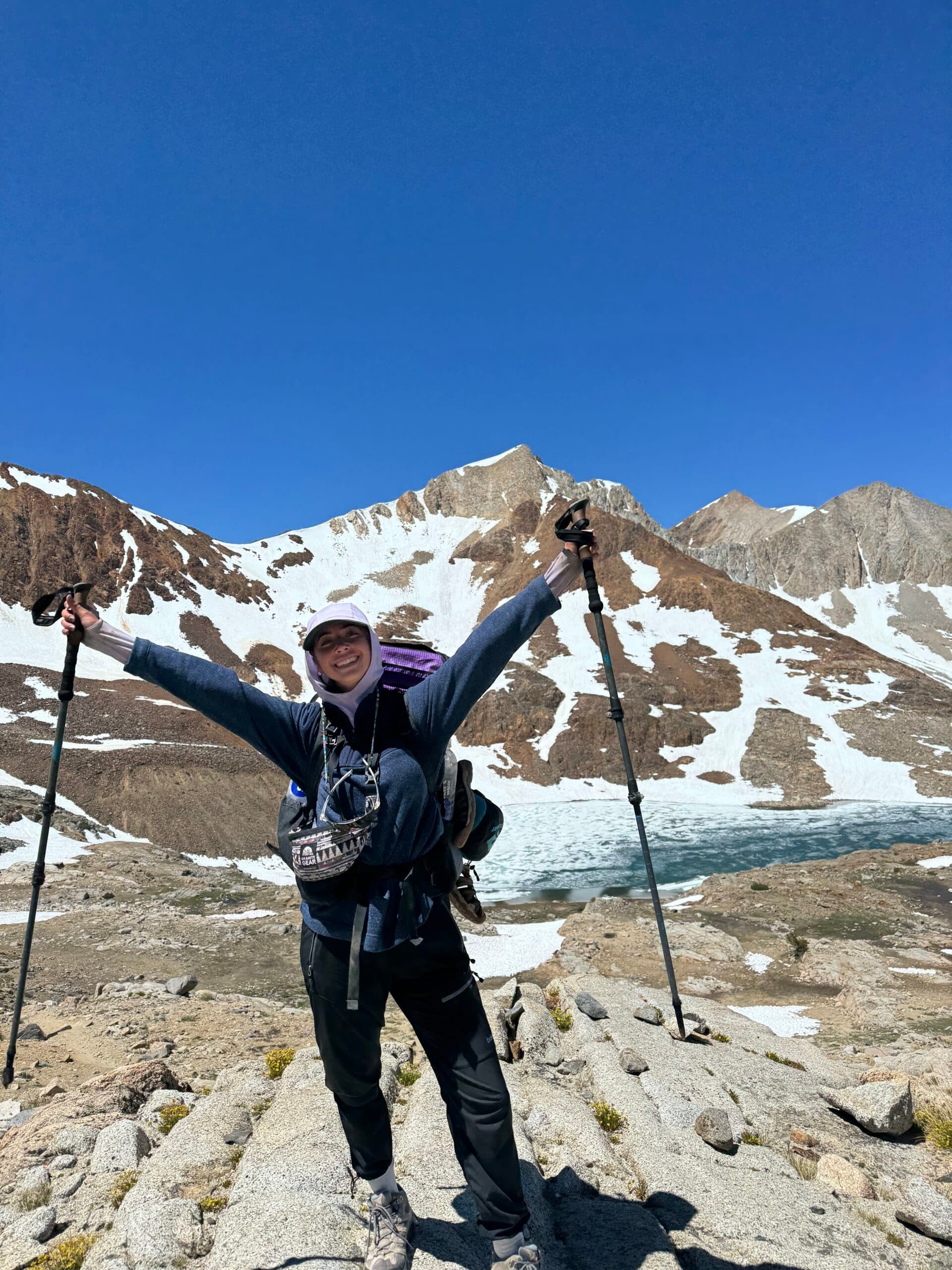 Katie Dominguez at the Pacific Crest Trail Southern Terminus at sunrise, holding hiking poles